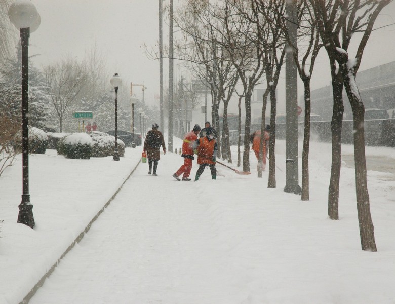 several men shovel sidewalk