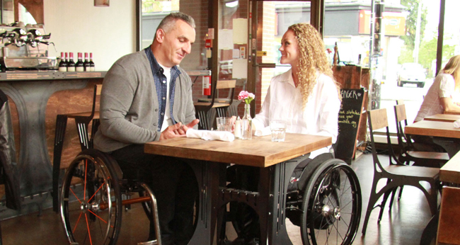 Couple sits in wheelchairs at cafe