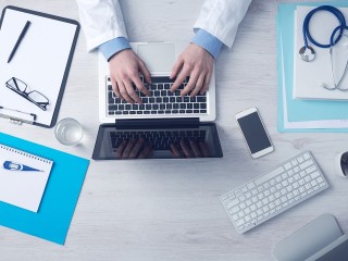 doctor types at laptop computer