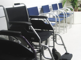 A wheelchair next to a row of plastic chairs