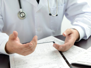 Doctor gesticulates over printed health records